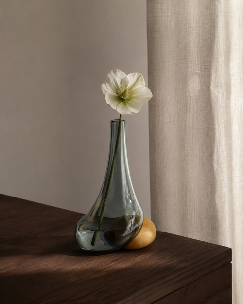 Stoneveil No. 003 smoke-blue glass and ochre stone bud vase styled with a white hellebore