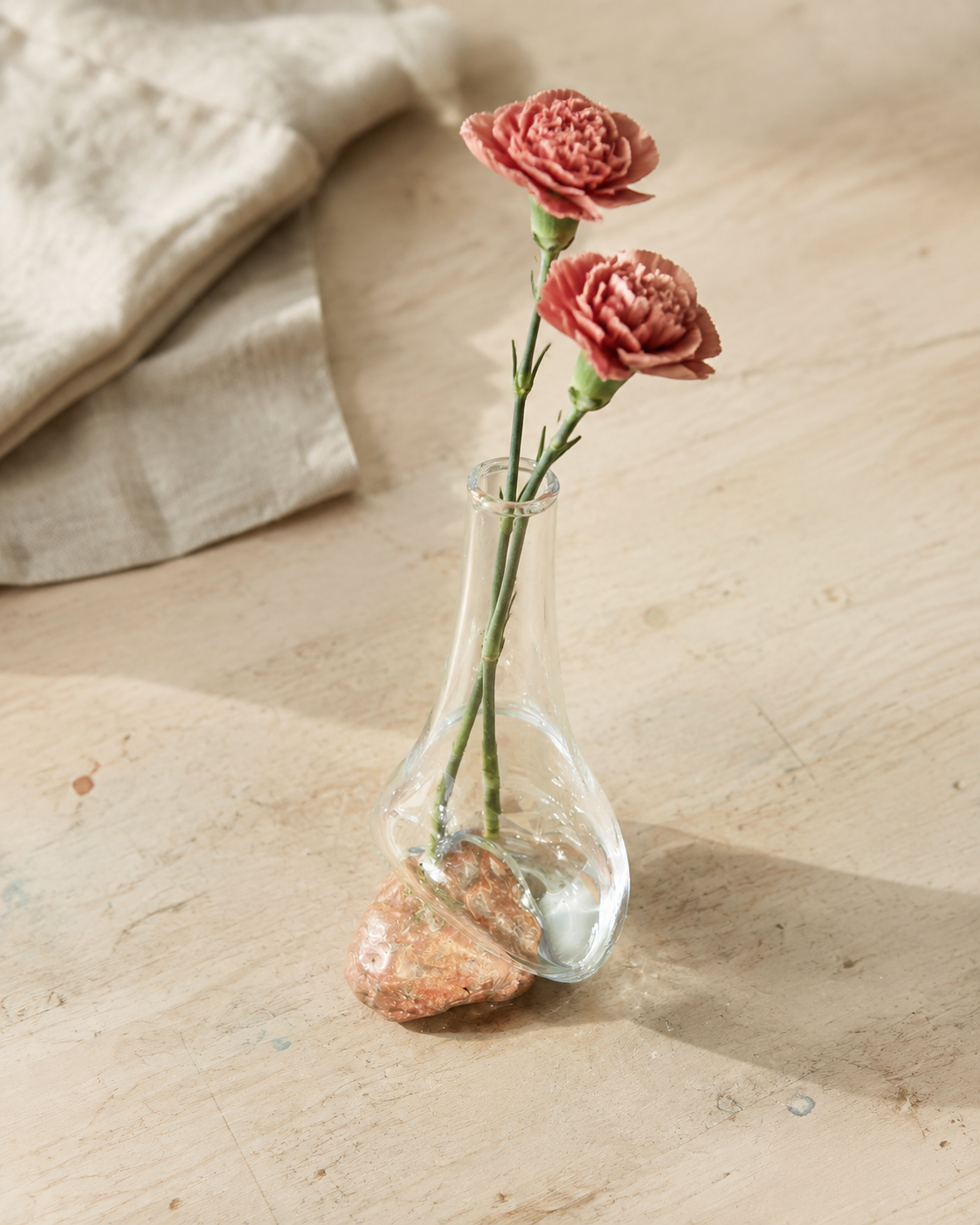 High-angle view of Stoneveil No. 004 styled with dusty rose carnations on an atelier table